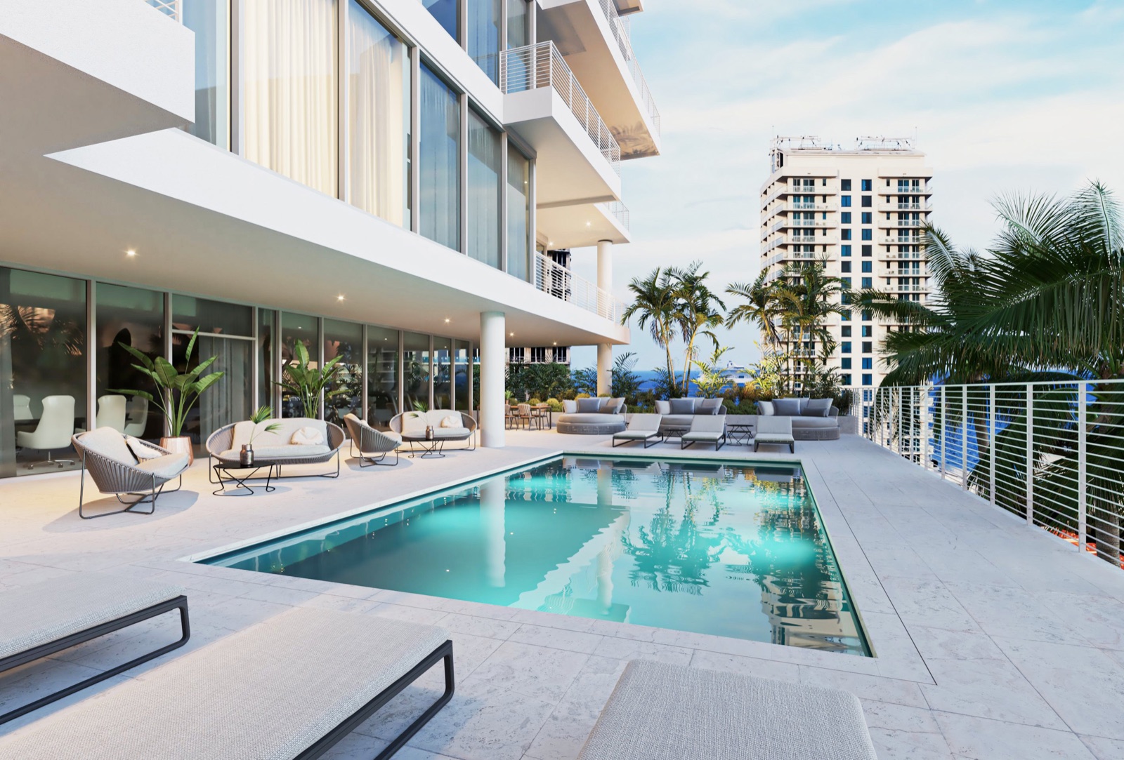 The Level 3 relaxation deck at The Terraces Fort Lauderdale Beach — a heated pool with private sun loungers, framed by white pavers and palms, with lounge seating and a summer kitchen alongside.