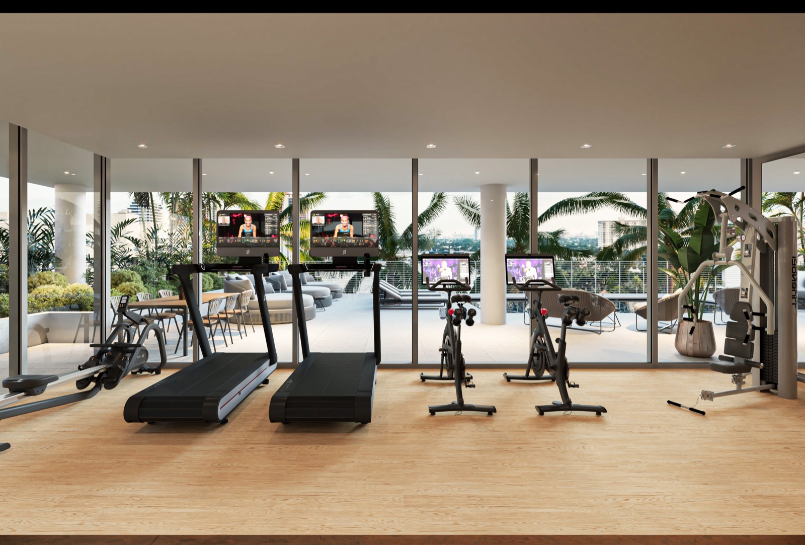 The fitness center at The Terraces Fort Lauderdale Beach — Matrix treadmills and spin bikes with floor-to-ceiling glass overlooking the pool deck and a dedicated area for yoga and mat exercise.